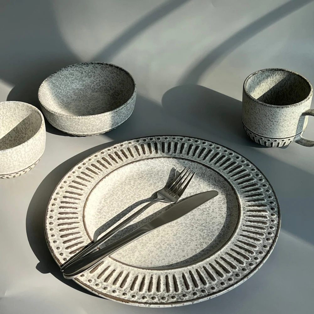 Official detail photograph of a patterned plate with cutlery, bowls and a mug