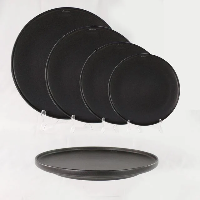 Official photograph of four dark round stacking plates and a side view