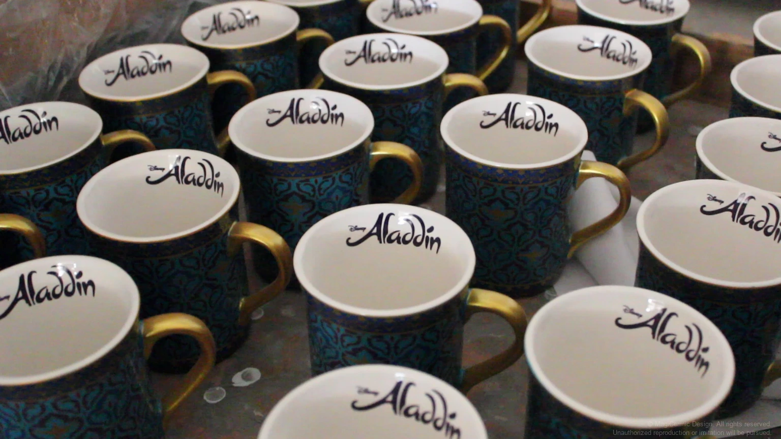 Grouped dark blue and gold Aladdin mugs with character name printed on the inner rim